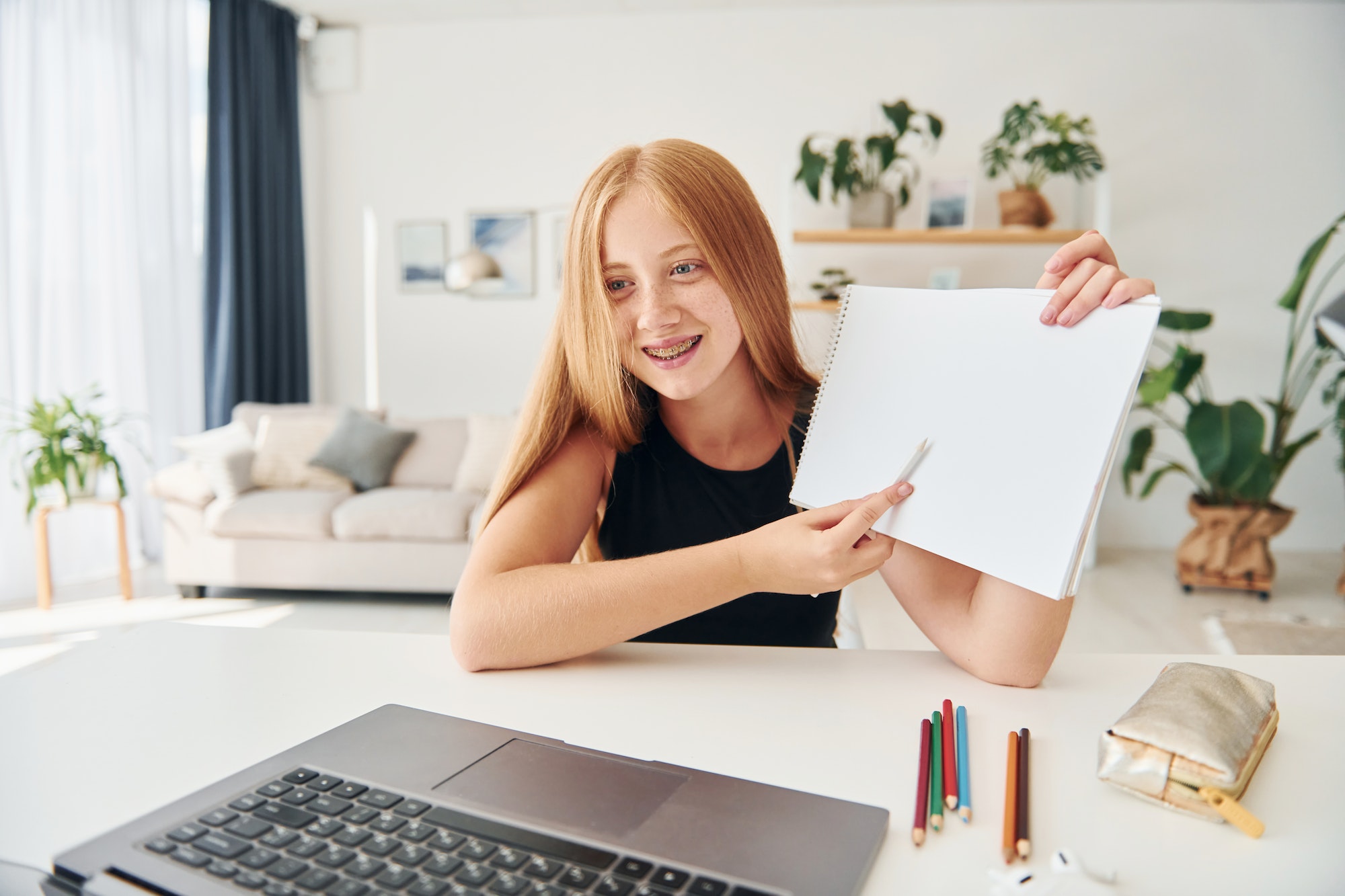 Online school. Female teenager with blonde hair is at home at daytime